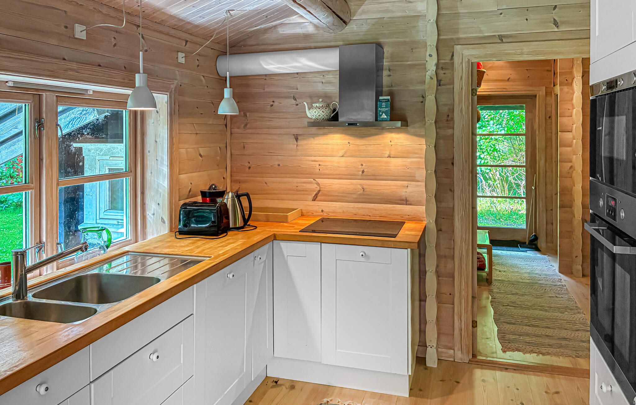 Una cocina moderna con paredes de madera, estufa integrada y un ventanal grande.