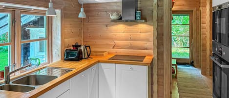 A modern kitchen with wooden walls, a built-in stove, and a large window.