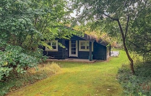 A log cabin with a porch, surrounded by dense foliage. - Lovely home in Tisvildeleje with WiFi (Tisvildeleje)