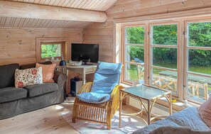 A cozy interior with a sofa, a wicker chair, a small table, and a TV. - Lovely home in Tisvildeleje with WiFi (Tisvildeleje)