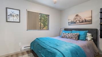 A bedroom with a bed, a window, and two wall-mounted pictures.