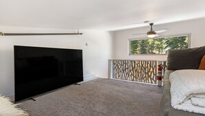 A living room with a flat-screen TV, a ceiling fan, a window with a view of trees, and a fire extinguisher. - Beautiful 1 Bedroom Vail Condo 700 meters from Cascade Lift (Vail)