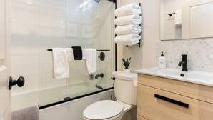 A modern bathroom with a glass-enclosed shower, a toilet, a sink with a mirror, and neatly arranged towels. - Beautiful 1 Bedroom Vail Condo 700 meters from Cascade Lift (Vail)