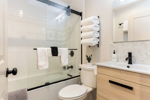 A modern bathroom with a glass-enclosed shower, a toilet, a sink with a mirror, and neatly arranged towels. - Beautiful 1 Bedroom Vail Condo 700 meters from Cascade Lift (Vail)
