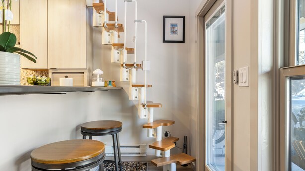 A modern kitchen with a white countertop, a wooden bar stool, and a hanging cat tree. - Beautiful 1 Bedroom Vail Condo 700 meters from Cascade Lift (Vail)