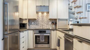 A modern kitchen with stainless steel appliances, wooden cabinets, and a patterned backsplash.