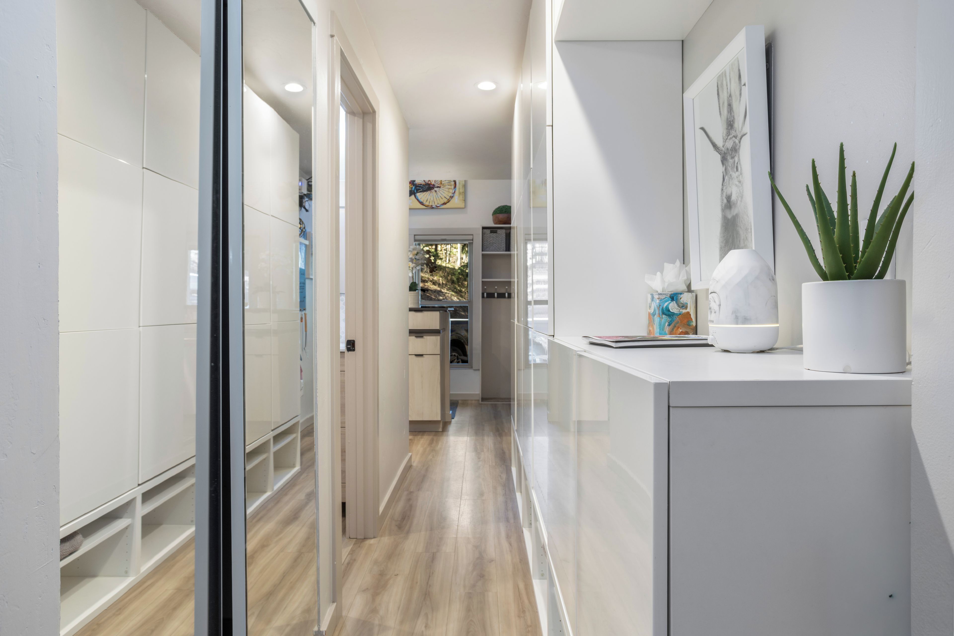 A modern hallway with a glass door leading to a kitchen area.