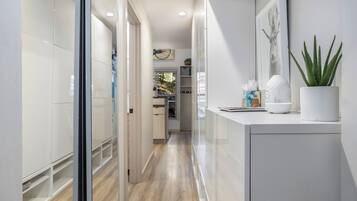 A modern hallway with a glass door leading to a kitchen area.