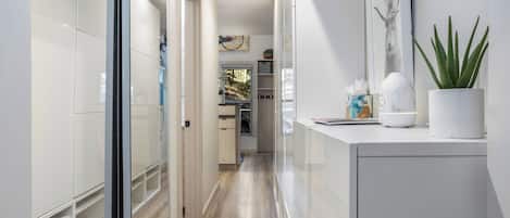 Un pasillo moderno con una puerta de cristal que da a una zona de cocina.
