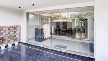 A modern interior with a glass entrance, a tiled wall with a floral pattern, and potted plants.