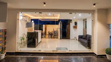 A modern interior with a glass entrance, a dining area with chairs and a table, and a sofa.