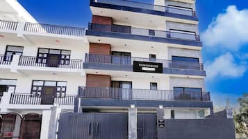 A multi-story building with balconies, a sign indicating it's a company-serviced property, and a gated entrance.