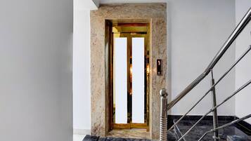 A modern elevator with a marble wall and a metal handrail.