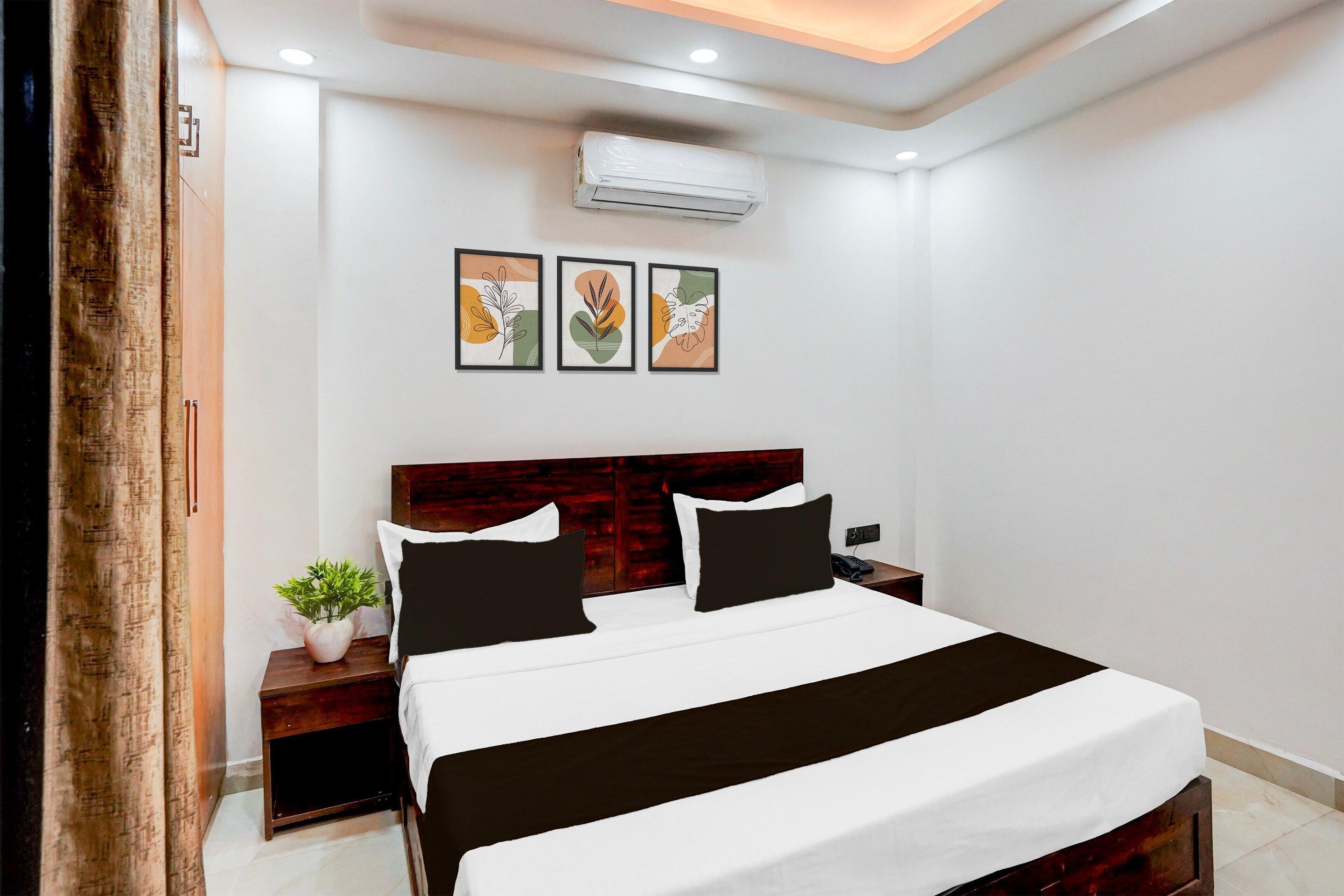 Ein Hotelzimmer mit Bett, Nachttischen, Klimaanlage und Wandbildern.