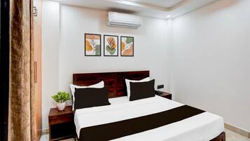 Ein Hotelzimmer mit Bett, Nachttischen, Klimaanlage und Wandbildern.