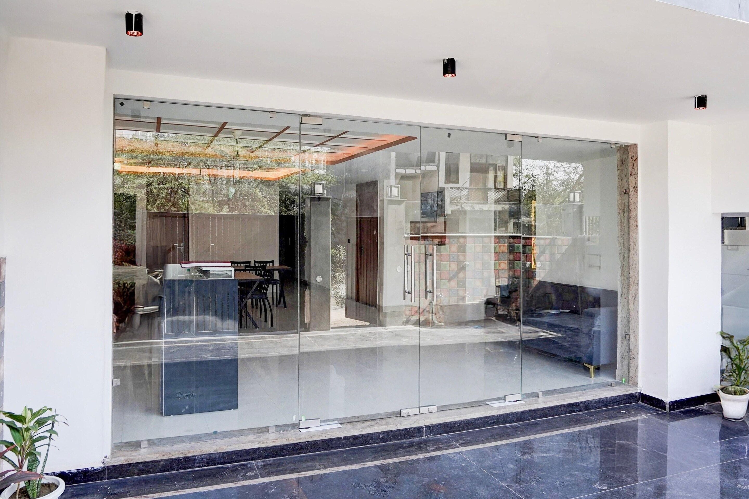 A modern interior with a glass partition, a seating area with a sofa and chairs, and a small table.