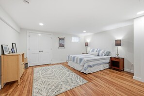 A bedroom with a bed, bedside lamps, a wooden dresser, a door, and a patterned rug. - Close to Mayflower Beach with deck, yard, and A/C. (Dennis)