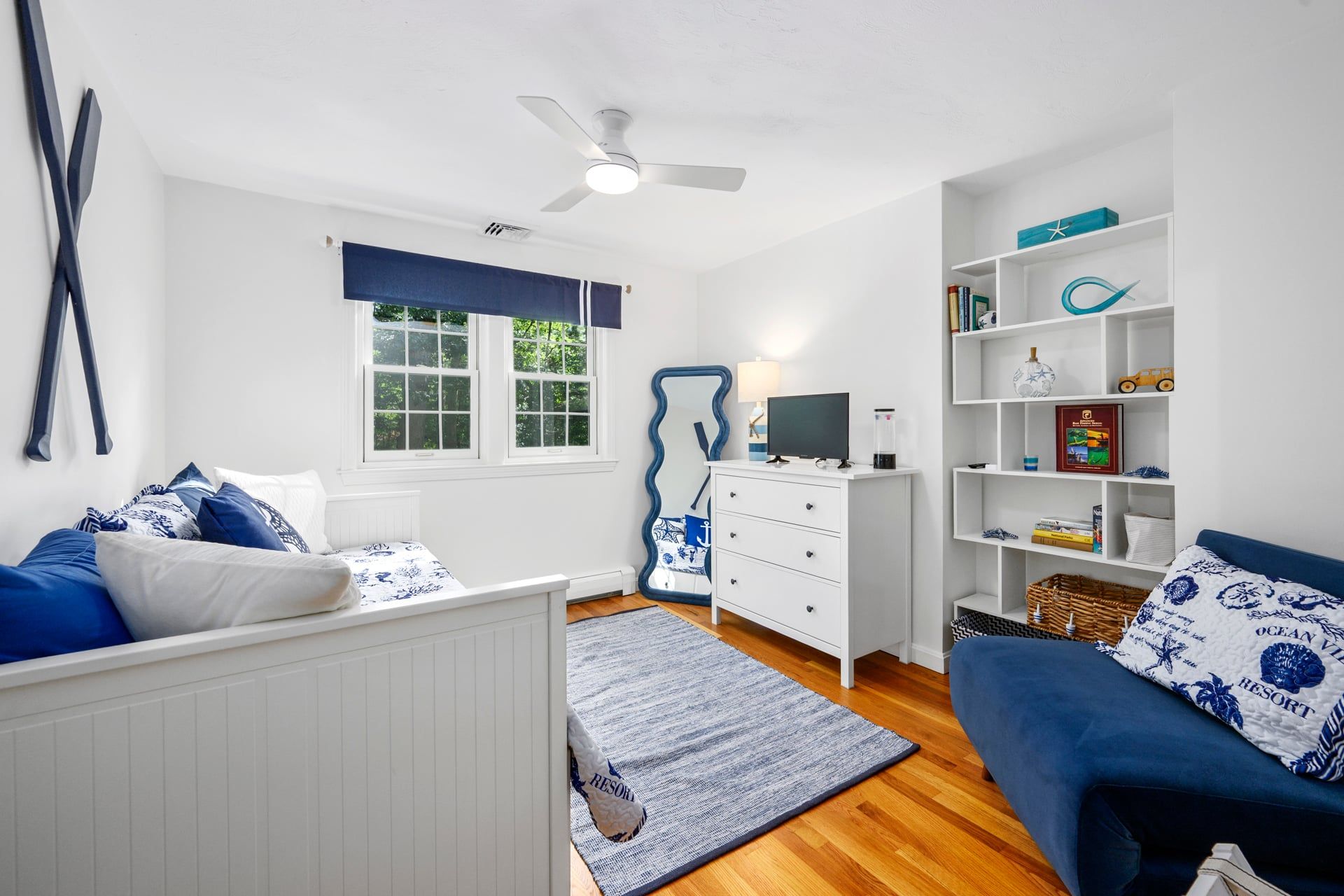 Una habitación con cama, escritorio, silla, estantería y ventana.