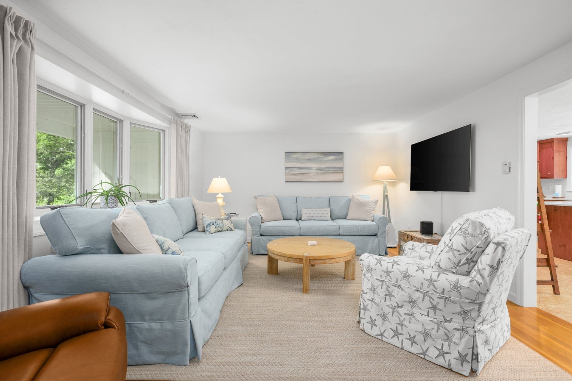 Una sala de estar con sofá, sillón, mesa de centro y televisor de pantalla plana.