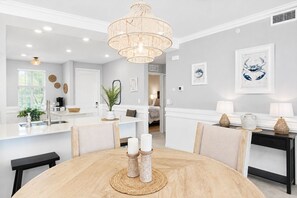 Cozinha moderna com ilha central, iluminação pendente e área de jantar com mesa redonda.