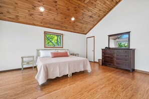 A bedroom with a wooden ceiling, a bed with a white bedspread, a dresser with drawers, and a framed picture on the wall. - Three Loons | Waterfront on Mooselookmeguntic! (Oquossoc)