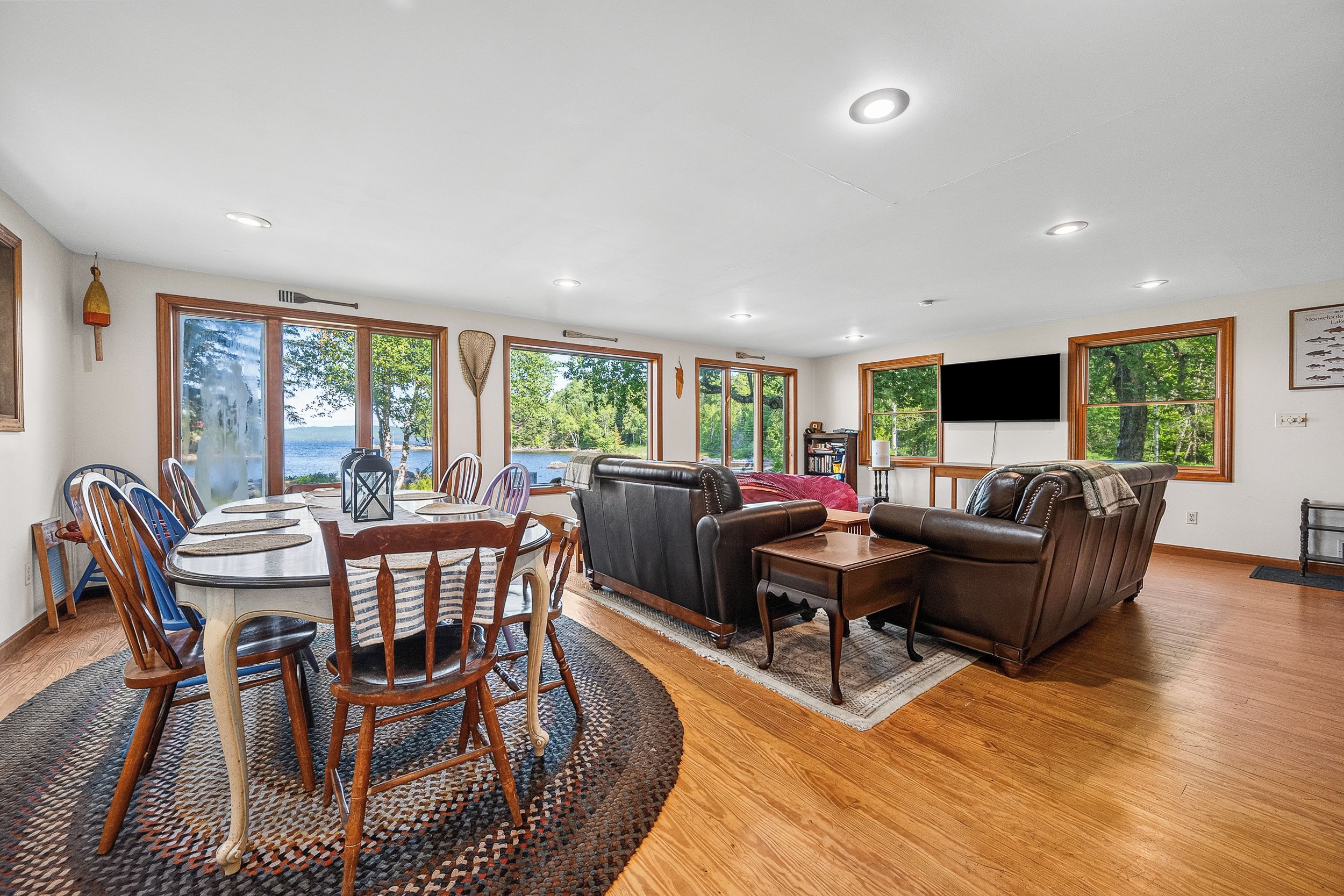 A spacious living area with a dining table, chairs, a sofa, and a television.