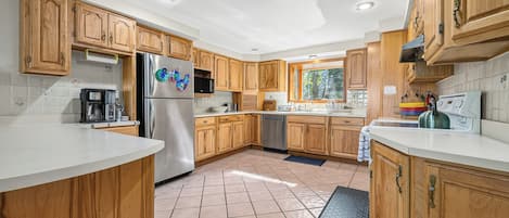 A modern kitchen with wooden cabinets, stainless steel appliances, and a large window.