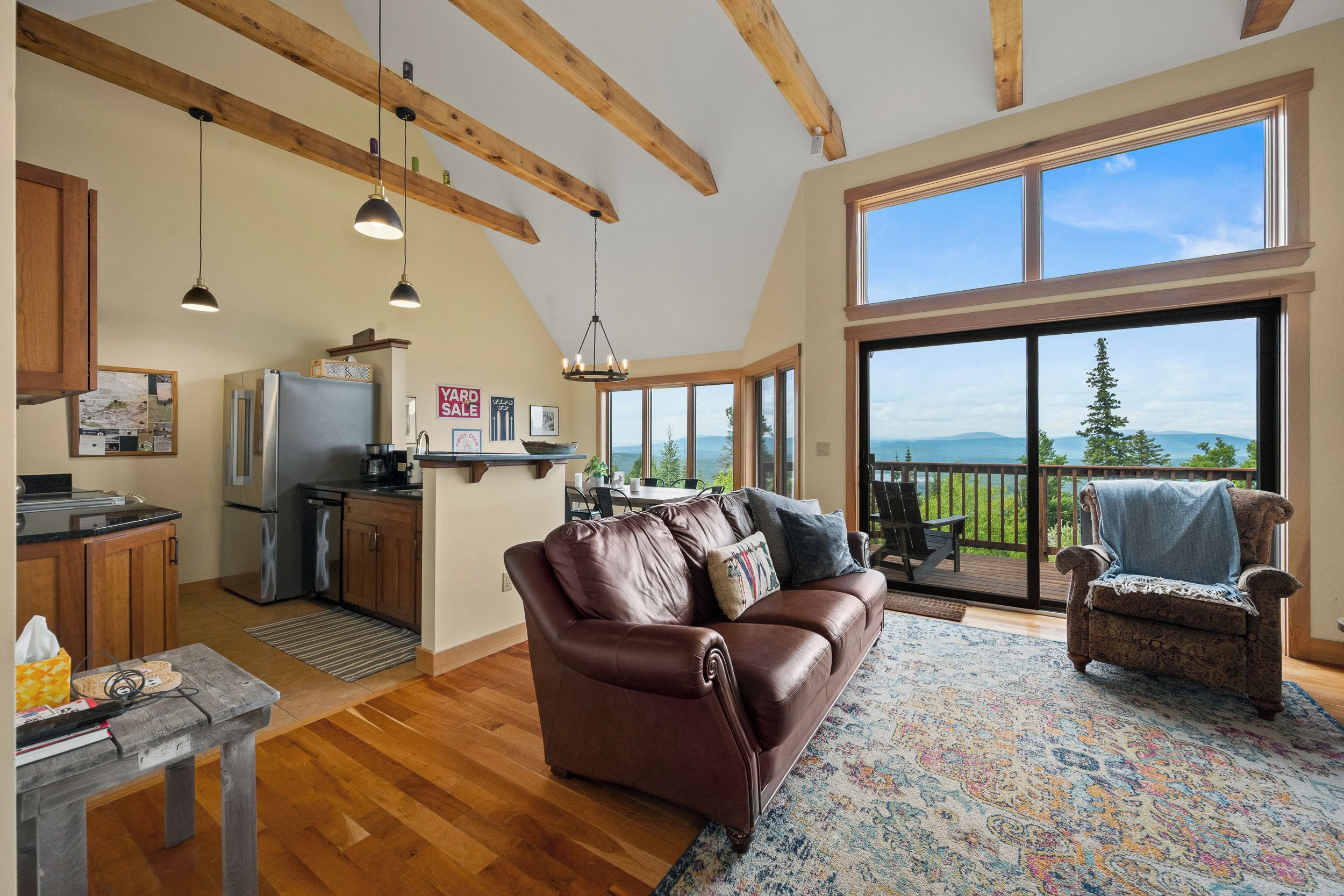 A spacious living area with a leather sofa, a dining table, and a kitchen with a refrigerator and coffee maker.