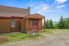Une cabane en bois avec une porte rouge, une cheminée et une plaque portant le numéro 16.
