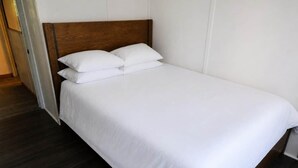 A single bed with a wooden headboard and white bedding in a room with dark flooring. - Mauna Kai, Princeville | 3 Bedrooms, AC & Pool (Princeville)