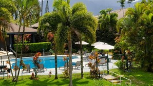 A pool area with lounge chairs and umbrellas, surrounded by palm trees and a mountainous backdrop. - Mauna Kai, Princeville | 3 Bedrooms, AC & Pool (Princeville)