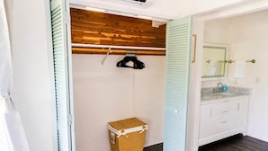 A bathroom with a wooden ceiling, a hanging rack, a wicker basket, and a white sink with a mirror. - Mauna Kai, Princeville | 3 Bedrooms, AC & Pool (Princeville)