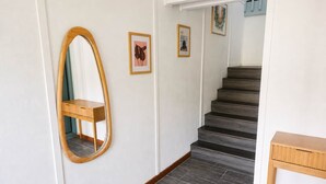 A staircase with a wooden handrail, a mirror, and framed artwork on the walls. - Mauna Kai, Princeville | 3 Bedrooms, AC & Pool (Princeville)