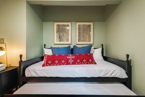 Ein Schlafzimmer mit einem Bett, zwei gerahmten Bildern an der Wand, einer Nachttischlampe und einem Nachttisch.