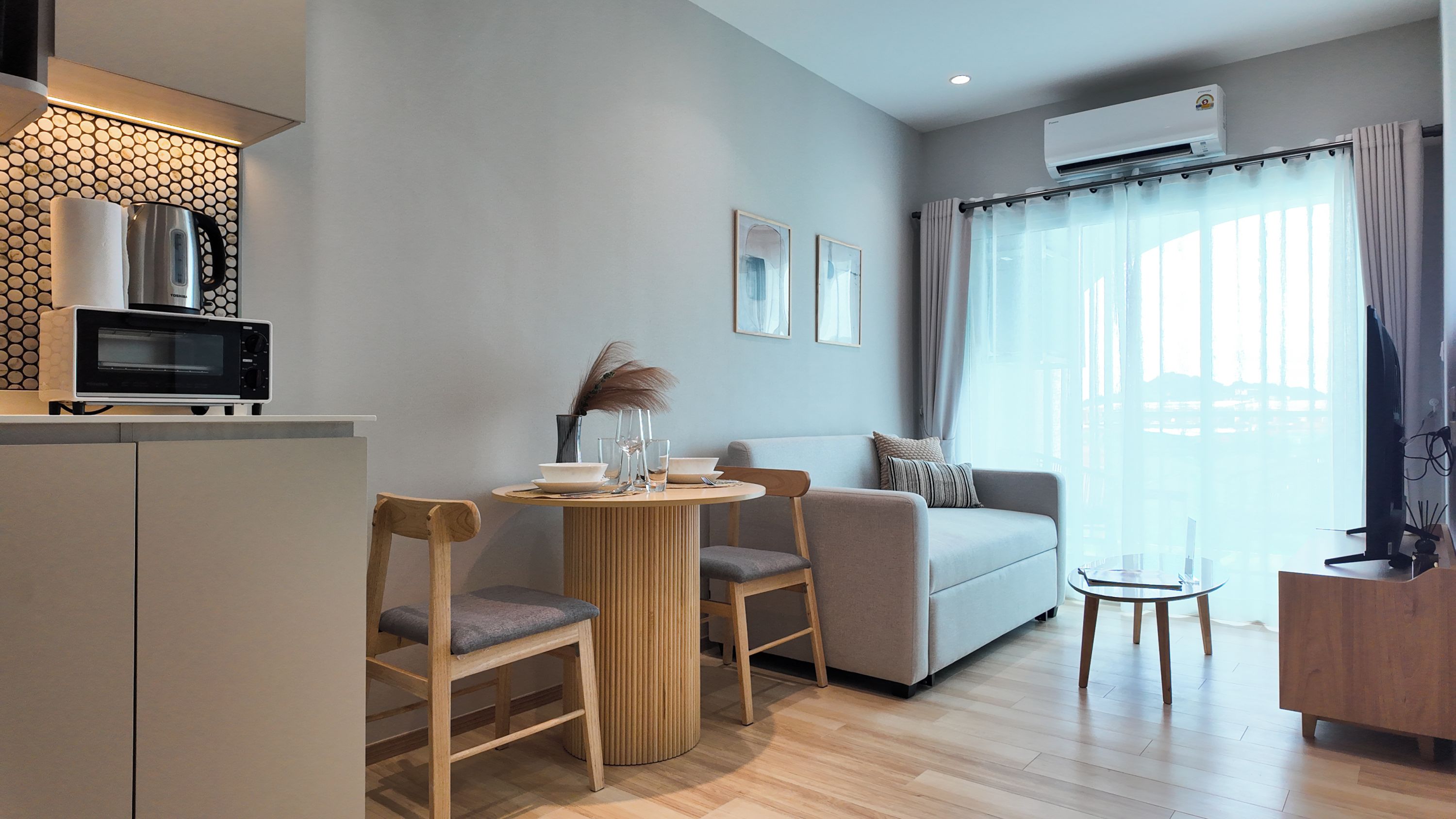 A modern living space with a kitchenette, a dining area, and a seating area with a sofa and chairs.
