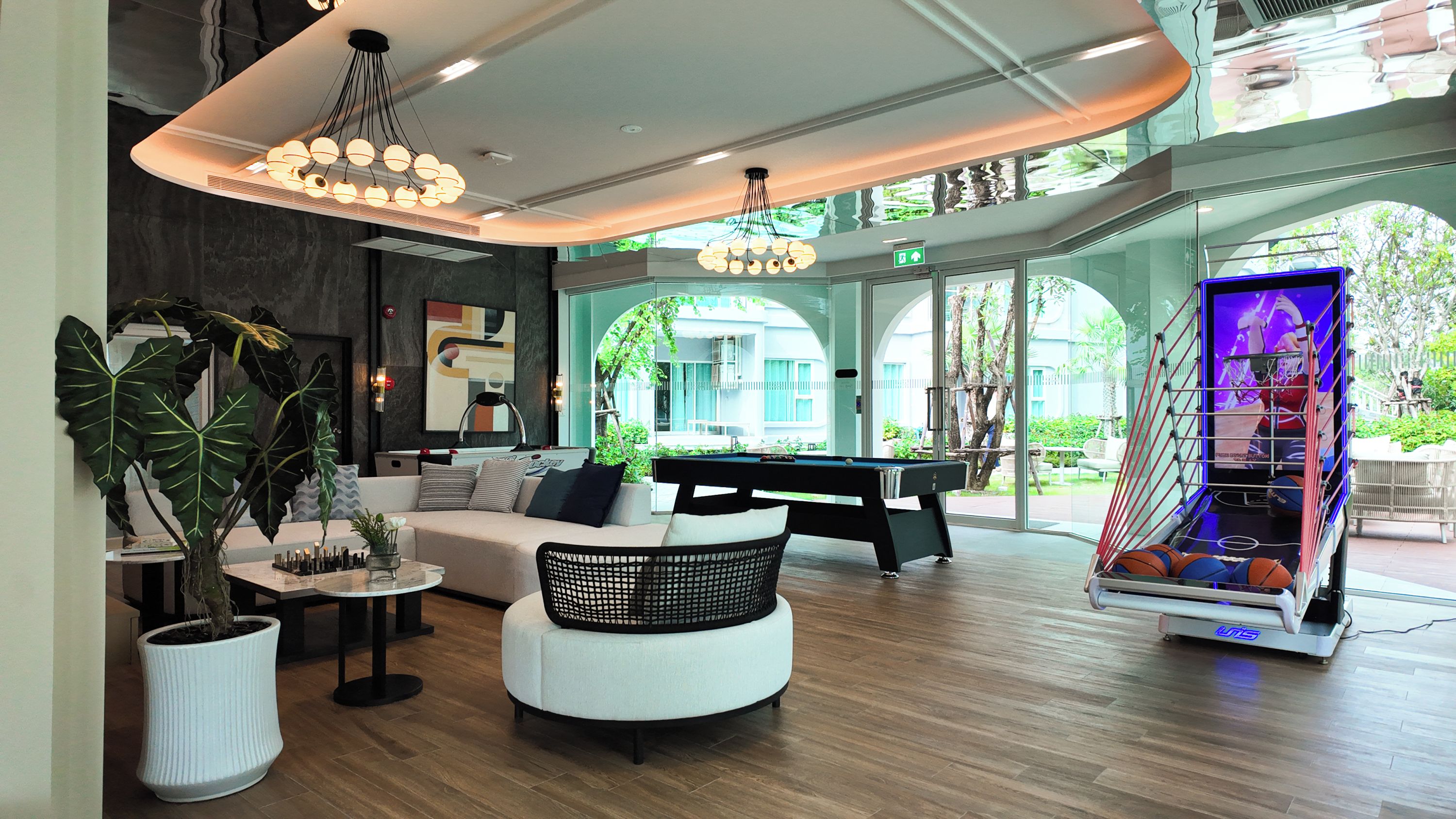 A modern lounge area with a pool table, comfortable seating, and a large window offering a view of the outdoors.