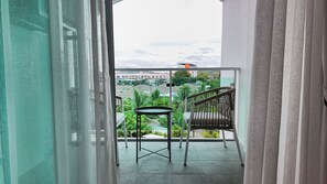 Un balcon donnant sur un quartier résidentiel, avec une chaise et une petite table.