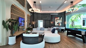 A modern living room with a pool table, a sofa set, and a television mounted on the wall. - Lumi 1br suite | Title Serenity Nai Yang (Tambon Sa Khu)