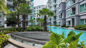 A modern hotel with a swimming pool surrounded by lush greenery and palm trees. - Lumi 1br suite | Title Serenity Nai Yang (Tambon Sa Khu)