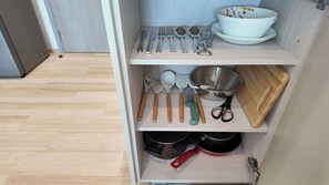 A kitchen cabinet with utensils, a bowl, a cutting board, and pots. - Lumi 1br suite | Title Serenity Nai Yang (Tambon Sa Khu)