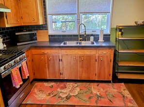 A kitchen with wooden cabinets, a stainless steel sink, a microwave, and a stove. - Wonderful 2-bedroom apartment in The Handsome Craftsman in Highland Square (Akron)