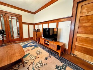 A traditional Japanese-style room with tatami flooring, a low wooden entertainment unit with a television, and a sliding door. - Wonderful 2-bedroom apartment in The Handsome Craftsman in Highland Square (Akron)