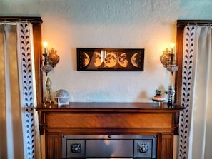 A fireplace with a mantel, two wall sconces, and a framed artwork above it. - Wonderful 2-bedroom apartment in The Handsome Craftsman in Highland Square (Akron)
