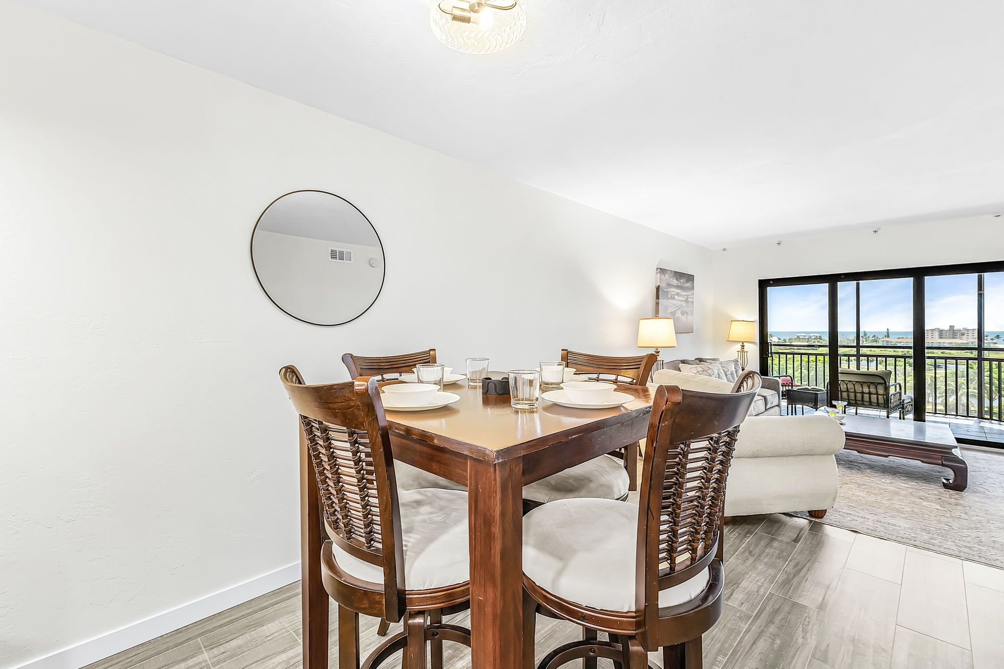 A dining area with a round table, chairs, and a mirror on the wall.