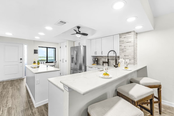 A modern kitchen with a central island, stainless steel appliances, and a view to the outdoors. - Bay Beach Retreat with Pool, Spa, Tennis, Pickleball and Waterfront Family Fun - Bay Beach - Roelens (Fort Myers Beach)