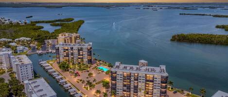 A high-rise hotel with multiple floors, a marina with boats, and a waterfront view.