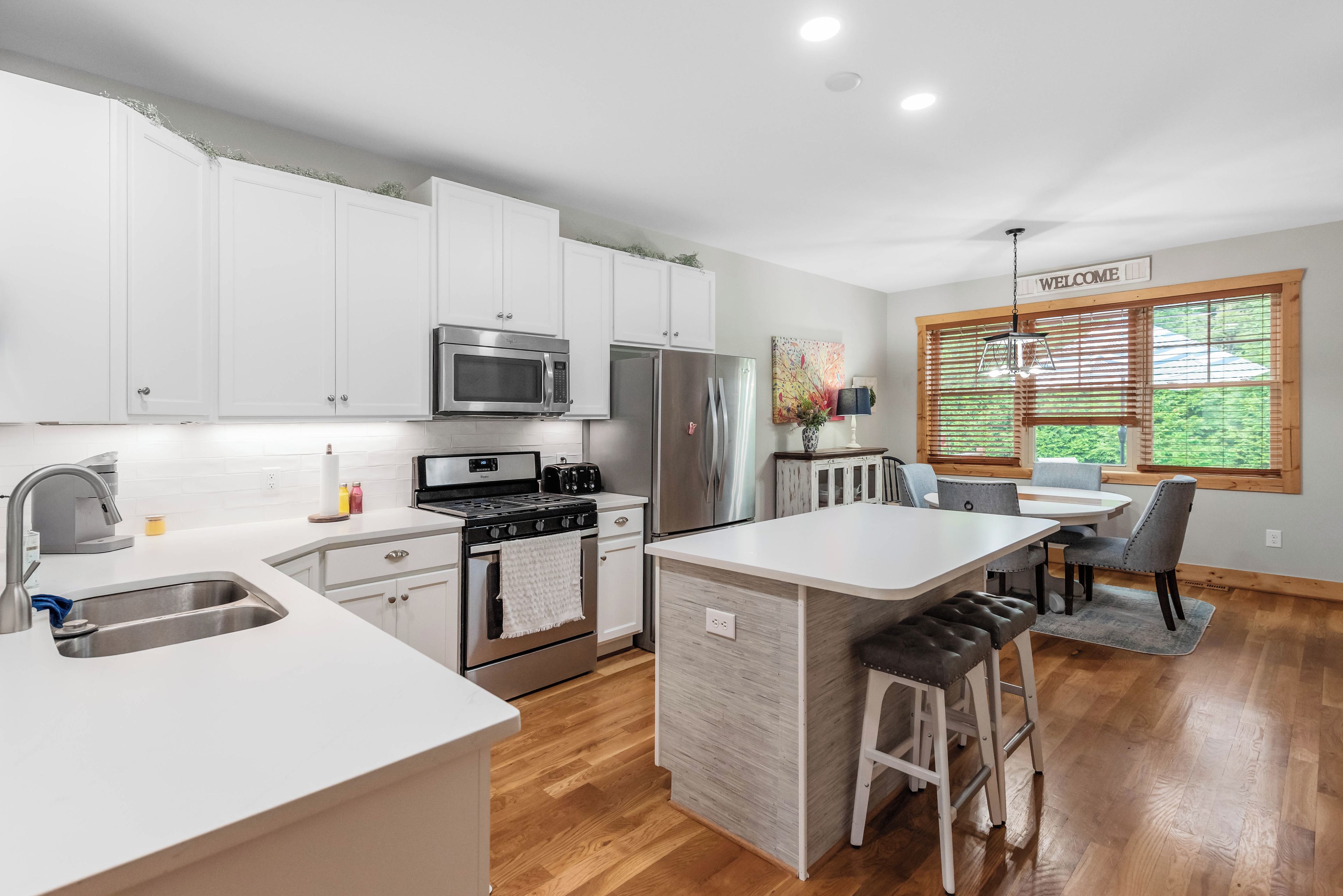 A modern kitchen with white cabinetry, stainless steel appliances, and a central island.