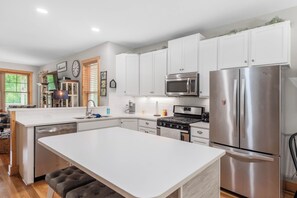 A modern kitchen with white cabinetry, stainless steel appliances, and a central island. - Mountain Gem - Minutes to Downtown WJ - Shops - Hiking (West Jefferson)