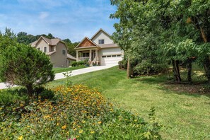 Una casa residenziale con veranda, garage e un prato curato con fiori gialli.