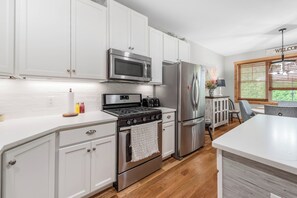 Una cucina moderna con mobili bianchi, elettrodomestici in acciaio inossidabile e pavimento in legno.